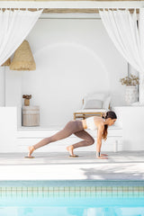 Woman exercising with sliders next to a pool.