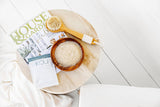 Close up of bath salts, magazine and bath brush on a table.