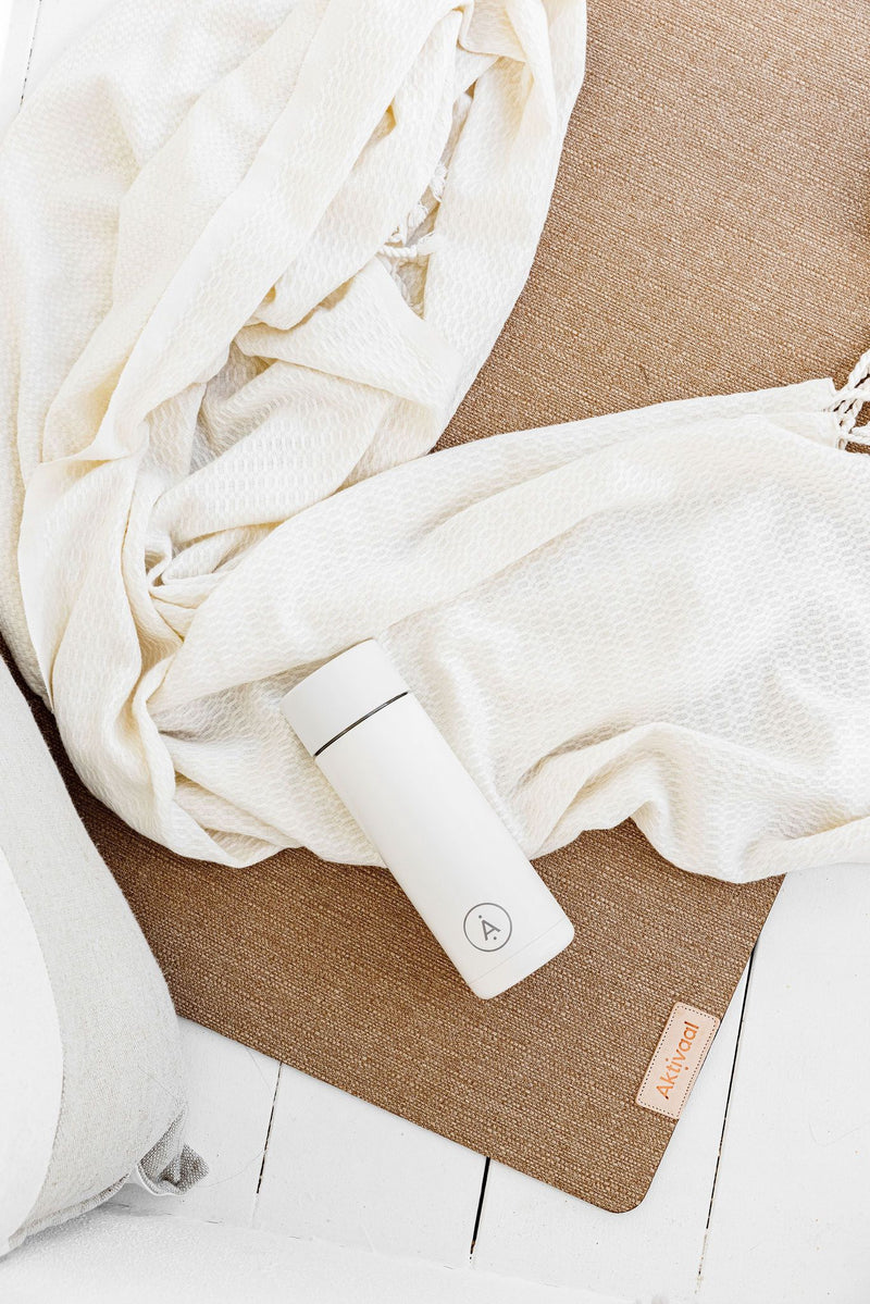 Turkish towel and ceramic water bottle on a jute mat. 