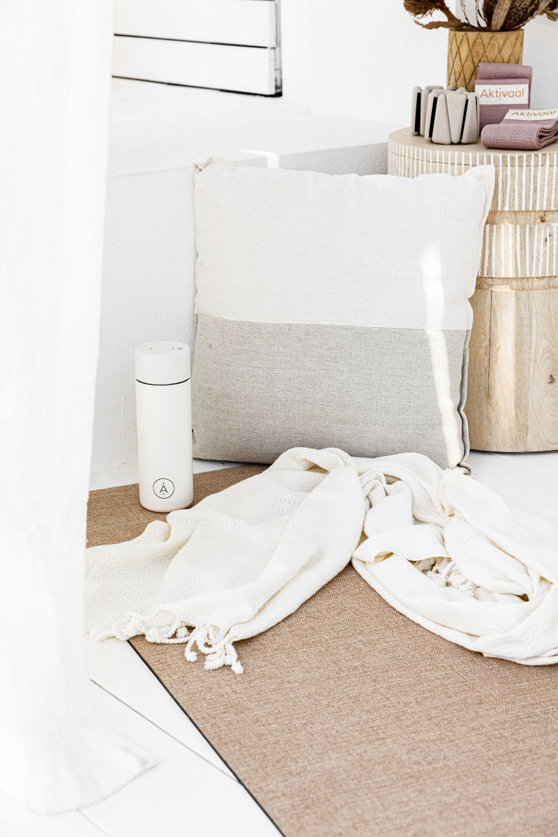 Water bottle sitting on a jute mat with a Turkish towel.